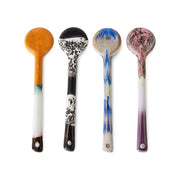 Four ceramic spoons with unique marbled designs on a white background