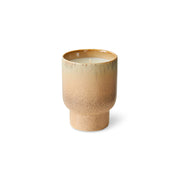 Beige ceramic candle with speckled texture on a white background