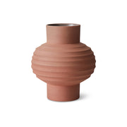 Terracotta-colored vase with ribbed texture on a white background
