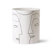 Cylindrical lamp shade with abstract face design on a white background